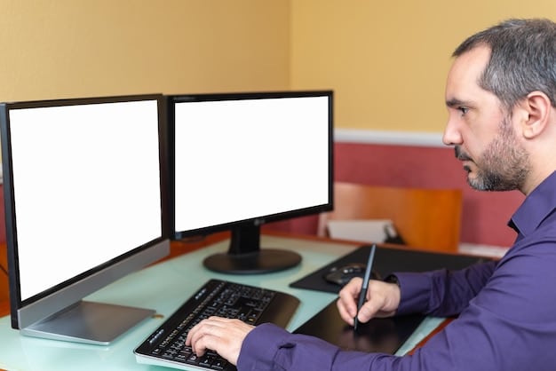 A person is sitting at a desk working on a computer with multiple monitors. The main monitor shows a diagram in the middle of the screen. The room is bright and spacious and looks comfortable.