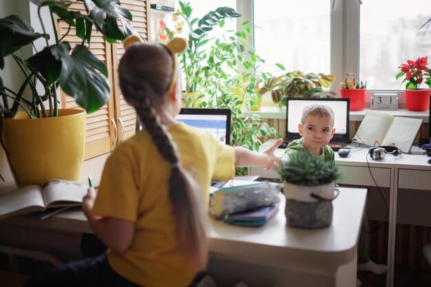 A parent sitting at a desk in a home office, smiling while talking on a video call. In the background, a child is quietly drawing at a small table, creating a sense of organized chaos.