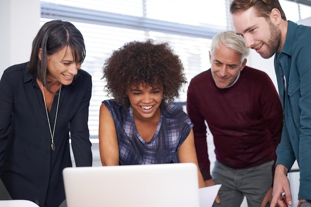 A group of diverse people looking at a laptop screen together, smiling, with graphs and charts displayed on the screen, representing market research and data analysis to understand the target audience for How to Build a Successful Online Store: A Step-by-Step Guide.