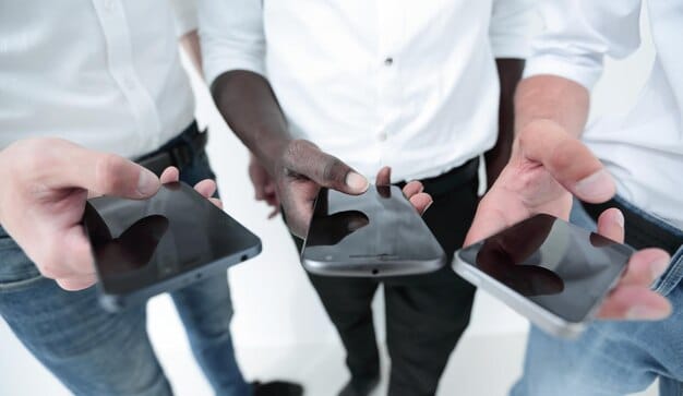 A close-up of diverse hands using smartphones to access financial apps, highlighting the accessibility and convenience of fintech solutions in underserved communities. This image represents 