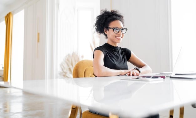 A person wearing glasses is sitting at a desk in a modern office at a computer reading 