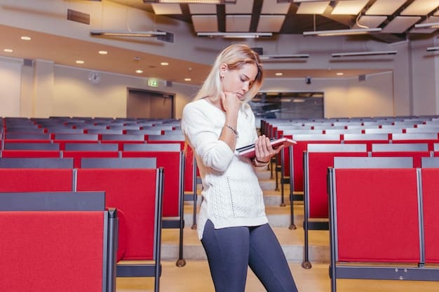 A well lit and professional looking lecture hall at a university with people sitting at desks listening to a guest speaker. The banner on the wall reads 